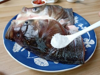 6、麻辣鱼头,在鱼头内部和外部都切上花刀,便于去腥入味,加盐一勺里外抹均匀。