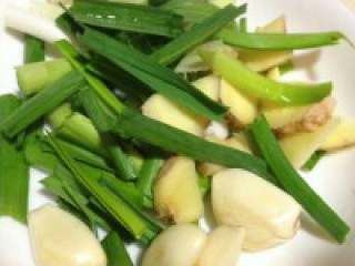 3、自制【牛肉火锅】,准备好的蒜苗切段，姜蒜拍碎备用。
