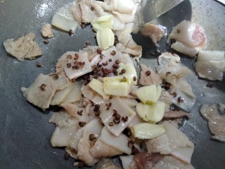 6、虎皮椒香小炒肉,将五花肉煸出六分熟,放入花椒,大蒜子,接的小火慢慢煸香。