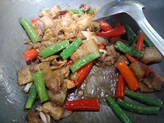 7、虎皮椒香小炒肉,煸香以后倒点适量酱油,料酒,蒸鱼汁鼓油,盐,鸡精。再放入青红尖椒,大火翻炒。