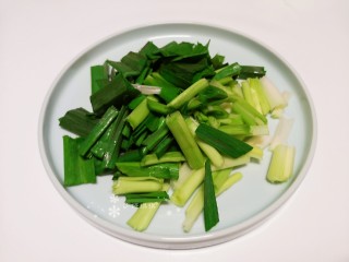 3、蒜苗炒香干,将蒜苗根茎用刀拍开（更易熟入味），切成小段。