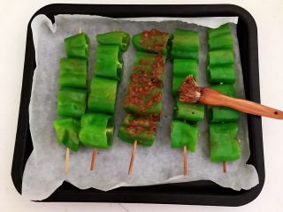 21、秘制烤辣椒,把烤盘取出来，给辣椒串刷一层秘制烧烤酱