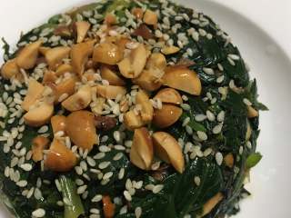 13、菠菜拌花生米,取一个小碗装满菠菜,然后倒扣在盘子里,上面在撒上花生碎和白芝麻