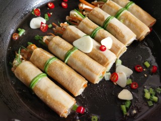 14、豆皮金针菇卷,加入些葱、蒜、辣椒炒香。