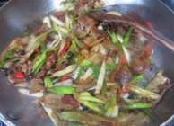 7、生爆盐煎肉,加入青红辣椒继续翻炒，肉片快断生的时候加入大蒜，白糖，鸡精调味，翻炒片刻起锅