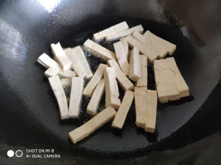 7、蒜薹炒豆腐,炒锅油热后，放入豆腐条。不要马上翻动它，把火调小一点，慢慢地来煎豆腐条。最好用不粘锅更容易些。