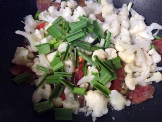 11、川味香肠炒菜花,最后放入蒜苗叶翻炒至变色即可。