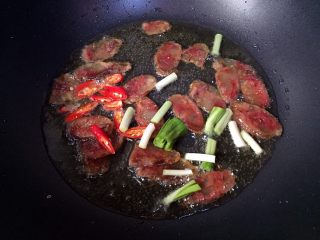 9、川味香肠炒菜花,接着放入小红尖椒和蒜苗头翻炒均匀。