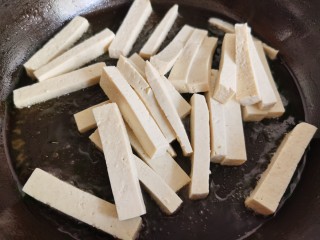 6、韭菜炒豆腐,平底锅烧热放油，放入豆腐条，加入少许食盐，让豆腐在煎制的过程中吃上盐味。