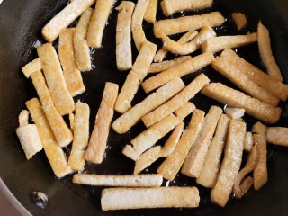 7、韭菜炒豆腐,豆腐条先不要着急翻动它，容易碎。等到下面的一层煎成金黄色之后再翻面，把另一面也煎成金黄色。这样煎过的豆腐不易碎而且好吃。