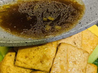 19、油菜豆腐,把煮好的豆腐夹起,放入装有油菜的盘子,并把锅里的料汁倒入;