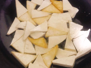 11、家常烧豆腐,隔几秒钟用铲子翻面，部分豆腐一面已经煎金黄了，仍需继续小火慢慢煎，勤翻面，直到全部都是两面金黄色