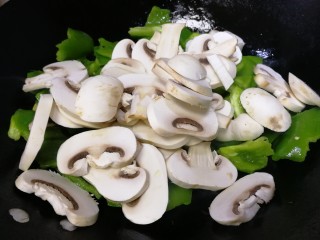 6、青椒炒口蘑,放入口蘑文火炒，把蘑菇炒软。