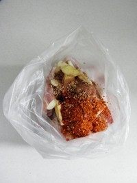 2、香辣烤排骨,取一个厚实点的保鲜袋，放入排骨，再放入姜蒜片，辣椒粉，麻椒粉和芝麻。