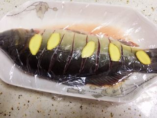 2、酸菜烧鱼,将鱼身两面用刀划花刀,用适量盐,料酒,涂匀腌味。再用姜片涂抹去腥味,一起腌制。