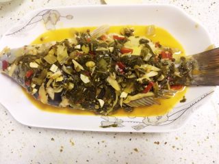 14、酸菜烧鱼,捞出一些酸菜段摆在鱼身上。