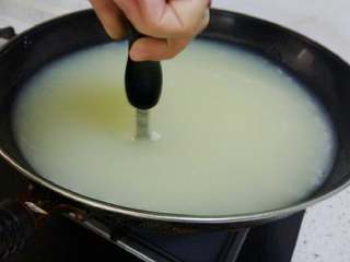 4、夏日甜品～凉糕,米浆全部倒入锅里搅拌均匀后，往锅里倒入石灰清水，继续不断搅拌。