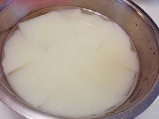 6、夏日甜品～凉糕,冷却后变成白色的凉糕。倒入一定纯净水，用刀将整块凉糕切成较大的块状。