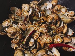 5、辣炒花蛤,将处理好的花蛤倒入锅中快速翻炒至均匀上色