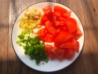 3、番茄烧豆腐,番茄清洗干净,切成小块,生姜去皮清洗干净切成末,蒜头去皮清洗干净切成末,葱清洗干净切成葱段,全部切好放入盘里待用。