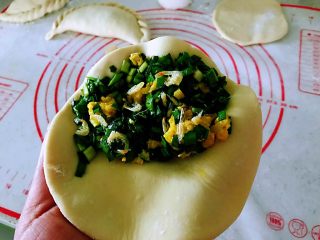 7、韭菜盒子,左手拿一个饼皮，在饼的一侧放入适量馅，不能太少。