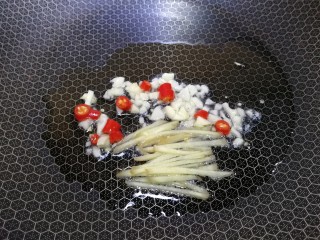 8、水煮千张,热锅凉油，放入姜丝，一半蒜末和小米辣，文火炒出香味。