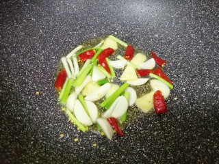 6、红烧土豆,锅底留余油，下入葱白、蒜片、生姜片和干红辣椒炒香。 