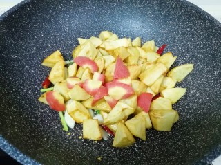 7、红烧土豆,下入红萝卜和煎好的土豆翻炒均匀。 