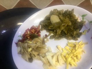 8、#年味#水煮酸菜滑肉片,七成热时将蒜姜泡椒泡姜酸菜全部倒入锅内炒