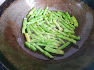 7、四季豆烧茄子,锅中放入适量植物油，放入四季豆翻炒至出现虎皮