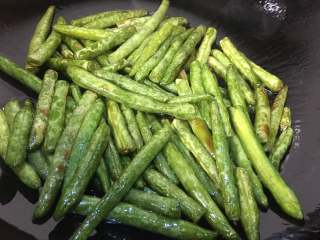 10、干煸芸豆,倒入刚才的四季豆，记得沥干水分，小火满煎至面皮发黄即可，这样炒出来的还是比较的嫩