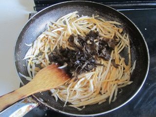 5、鱼香杏鲍菇,煸炒至杏鲍菇丝微微发软后下入黑木耳丝,一起翻炒;