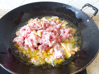 5、冷吃兔,炒锅上火烧热，倒油烧至五成热，将腌好的兔肉及生姜块倒入。