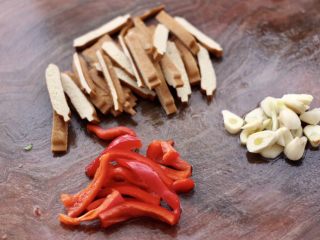 3、小白菜素炒香干,把豆干洗净用刀切成条，红椒切条，大蒜去皮切片。