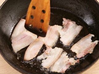 4、四川正宗盐煎肉,炒锅中倒一点点油抹匀，以小火加热，把腌好的五花肉擦干水分后放入锅中，用小火焙出油，直到肉片出香味，微微发黄变卷曲，然后盛出备用。