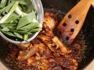 6、四川正宗盐煎肉,将肉片倒回锅中，加入青蒜蒜苗炒匀，加入少许糖调味即可。