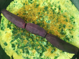 13、菠菜蛋卷,将提前煮好的小紫薯剥皮后整齐的放在蛋饼上