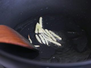 6、炒三脆,中火加热锅中的油，四五成热，放入姜片爆香。