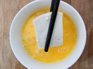 5、鱼香脆皮豆腐,把切块的豆腐,放入鸡蛋液中,让鸡蛋液,粘满豆腐