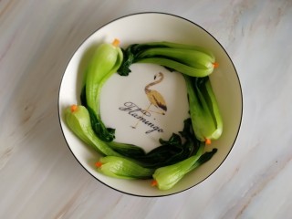 4、香菇油菜,沥干水后摆入盘中，把切好的胡萝卜菱形块塞到油菜头部十字口中