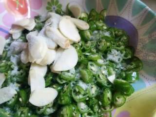 3、#地方菜#醋辣子,在加了蒜瓣的辣椒圈上撒上适量精盐和味精腌制五分钟