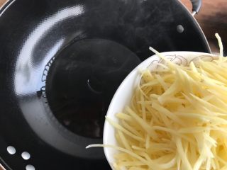 7、蒜香酸辣土豆丝,开最大火,待锅内油冒烟的时候,倒入土豆丝