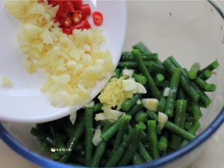 6、响油豇豆,豇豆捞出，放入大碗中，将葱、姜、小米椒等材料倒入豇豆中。