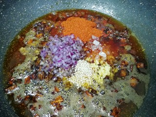 14、菌菇素辣酱,放入白芝麻、辣椒粉、冰糖碎、洋葱碎末和生姜碎末，转小火炒至辣椒出红油。