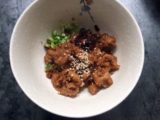 20、四川乐山名小吃—粉蒸肉卡饼,取适量粉蒸肉放入香菜小葱碗中，加入适量油辣椒，芝麻拌匀。