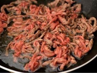 4、干煸牛肉丝,加入牛肉丝，大火翻炒1-2分钟，牛肉会出水；把水倒掉，吧牛肉丝归拢在锅的一边。