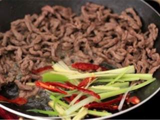 5、干煸牛肉丝,倒油 ，中火炒生姜丝 、葱 和干辣椒 。