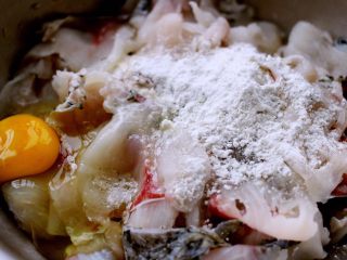 4、#辣味#麻辣水煮鱼,鱼肉片中加入调料包、料酒和一个鸡蛋搅拌均匀后腌制10分钟