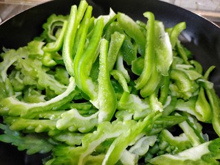 4、下饭苦瓜,倒入青椒混合翻炒，开小火烘焙苦瓜的部分水分