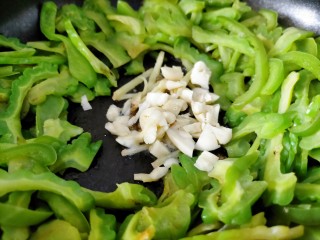 9、下饭苦瓜,放入大蒜，用筷子翻炒搅拌调料，别炒糊了